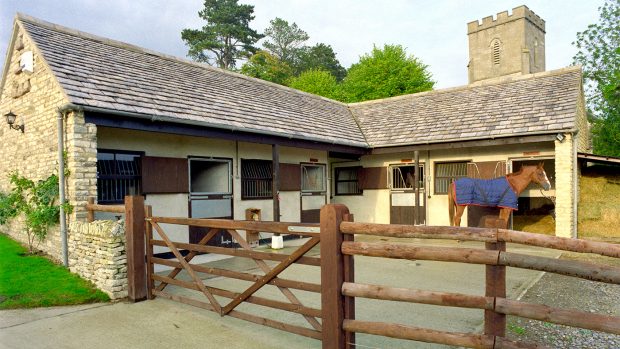 Renovating stable yard A28AG6 Horse stands outside small stone stable block