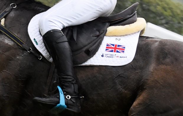 A close up of an event rider's leg showing the union flag on a white saddle cloth