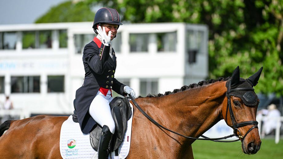 Ros Canter waves to the crowd from onboard Izilot DHI after going into the Badminton Horse Trials dressage lead